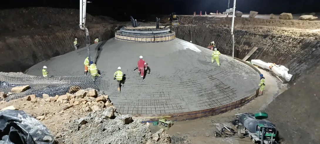 A number of workers in high visibility clothing at the base of one of the new wind turbines at Long Burn in Scotland