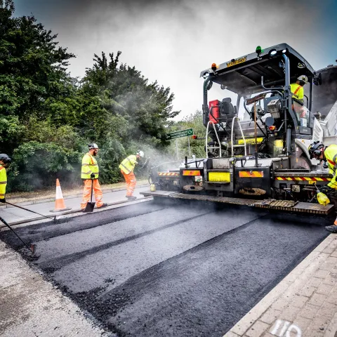 Aggregate Industries workers resurfacing a road with tools and machinery.