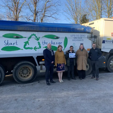 Representatives from AI with the winner of the competition, a teacher and representatives from PECT and Milestone standing in front of the winning design on the lorry. 