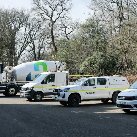 Various construction vehicles with Holcim branding in a car park